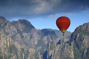 A red balloon floats on blue sky and mountain background in Vang Vieng, Laos 