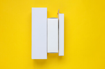 Different shapes of white cardboard boxes for products on a yellow background. Mockup for design
