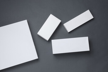 Different shapes of white cardboard boxes for presentation products on dark gray background. Mockup...