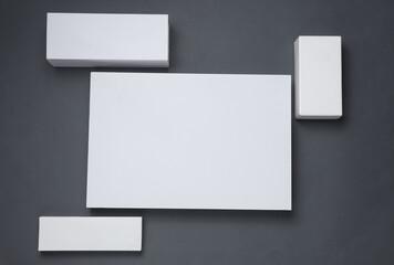 Different shapes of white cardboard boxes for presentation products on dark gray background. Mockup for design. Top view