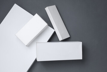Different shapes of white cardboard boxes for presentation products on dark gray background. Mockup...