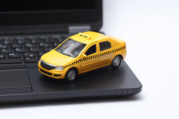 Toy taxi car on laptop keyboard close-up