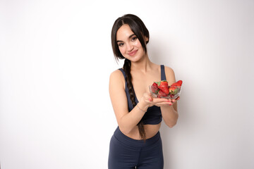Beautiful sport woman eating strawberries isolated on white background