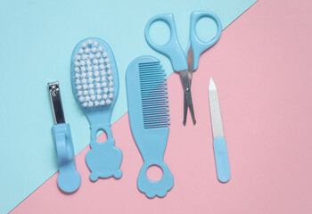 Baby care set on a blue-pink background. Scissors, comb, nail file, tweezers. Top view
