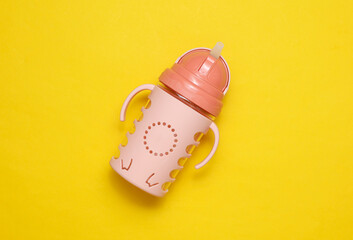 Drinking bowl for baby on yellow background. Top view