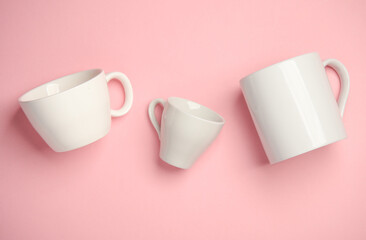 Three white ceramic cups on a pink background