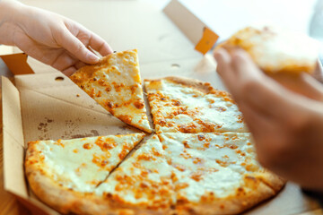 A girl's hand grabbing a cheesy slice of pizza