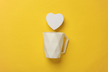 White cup with heart on yellow background. Valentine's day concept