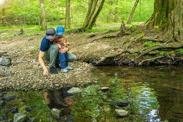 Dad with son toddler hiking together at sping forest near the river. 