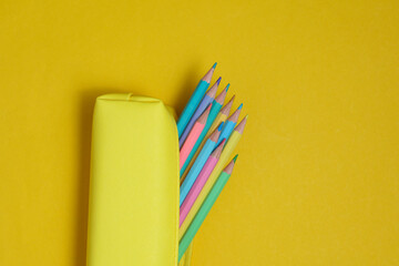 School pencil case with colored pencils on a yellow background. Back to school concept