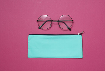 Blue school pencil case with eyeglasses on a pink background