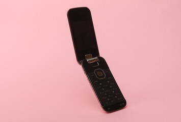 Outdated flip cell phone on pink background
