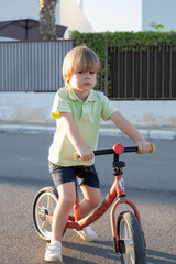 Portrait little cute adorable caucasian toddler boy enjoy having fun riding exercise bike in city park road.
