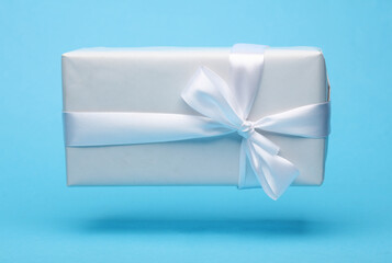 White gift box with bow mockup floating on blue background