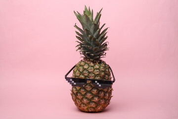 Pineapple with sunglasses on a pink background. Summer mood