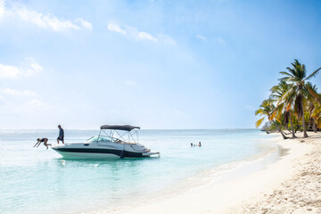 People enjoying themselves in a small boat floating in the ocean near a beach. The scene is calm, relaxing and fun. Concept of tourism, enjoyment, summer and relaxation.