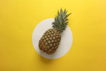 Pineapple on yellow background with white circle. Minimalism. Conceptual summer photo. Top view