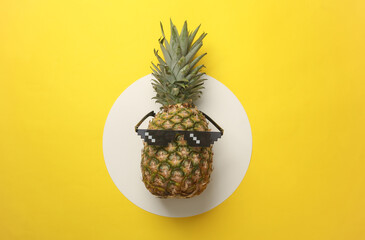 Pineapple with sunglasses on a yellow background. Summer mood. Top view