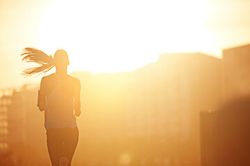 Woman, running and silhouette in sunrise for exercise with fitness, development or speed by buildings in city. Girl, person and athlete with training, workout and outdoor on metro road by skyscraper