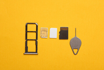 Smartphone Tray with SIM and micro SD memory cards on a yellow background. Flat lay