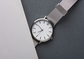 Women's wrist analog watch with metal or silver strap on gray background. Flat lay. Top view