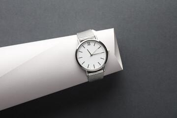 Women's wrist analog watch with metal or silver strap on gray background. Creative layout