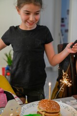 High resolution close up portrait image of a young girl blowing her birthday candle on a cheese burger- Israel