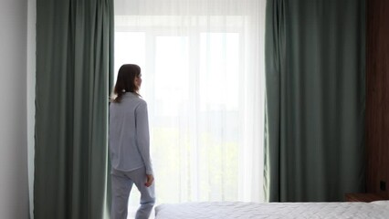 Woman is closing curtains on the window. Sunny day. Sunshine and warm at home. 