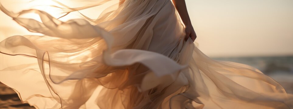 A close-up view captures a woman in a light beige dress billowing in the wind, creating a sense of movement and freedom. There're a sea or the ocean with sand dune on the background.