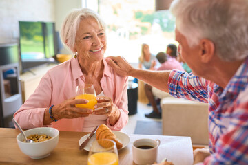 Grandparents Eating Breakfast Together With Three Generation Family In Background