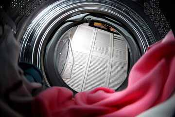 Clothes in washing machine indoors, view from inside. Laundry day