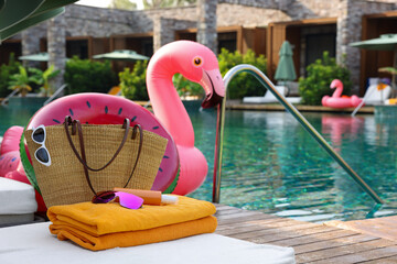 Beach accessories on sun lounger, inflatable ring and float near outdoor swimming pool, space for...