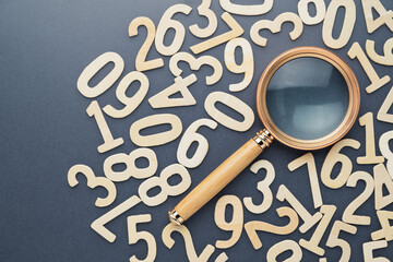 A magnifying glass and random wooden numbers, find the answer about numbers, mathematics learning