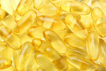 Yellow vitamin capsules as background, top view