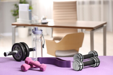 Many different sports equipment on mat indoors