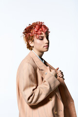 A vibrant, red-haired woman confidently wears a stylish coat.