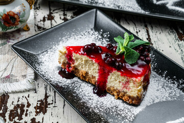 Delicious cheesecake with berry jam on plate on wooden background. Sweets, dessert and pastry, top...