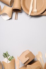 Eco friendly food packaging. Paper containers, tableware and twigs on light grey background, flat...