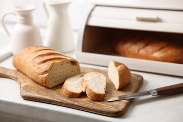 Wooden bread basket with freshly baked loaves on white marble table in kitchen