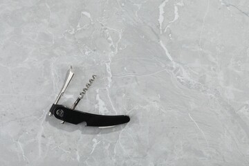 One corkscrew (sommelier knife) on grey marble table, top view. Space for text