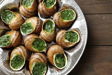 Delicious cooked snails on wooden table, top view