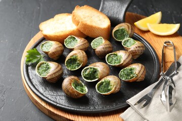 Delicious cooked snails served on grey textured table