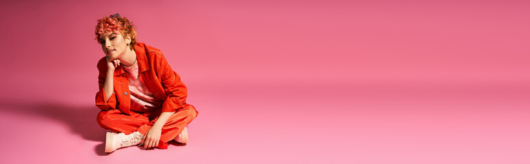 Extraordinary woman sitting gracefully on pink surface with matching background.