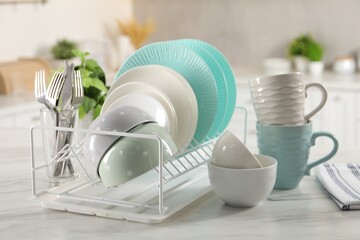 Many different clean dishware, cups and cutlery on white marble table in kitchen