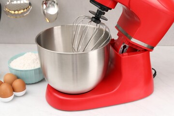 Modern red stand mixer, flour and eggs on white table in kitchen