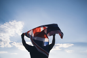 Man holding British flag against blue sky