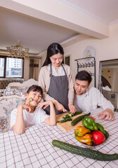 A family of three with vegetables at the table