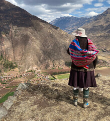 photo d'une femme de dos avec des vêtements typiques péruviens colorés. Elle regarde le paysage...
