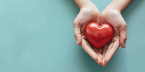 Fototapeta premium Woman hands holding red heart on solid light blue background. Health care, organ donation, cardiac health problems.