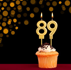 Birthday candle with cupcake - Number 89 on black background with out of focus lights